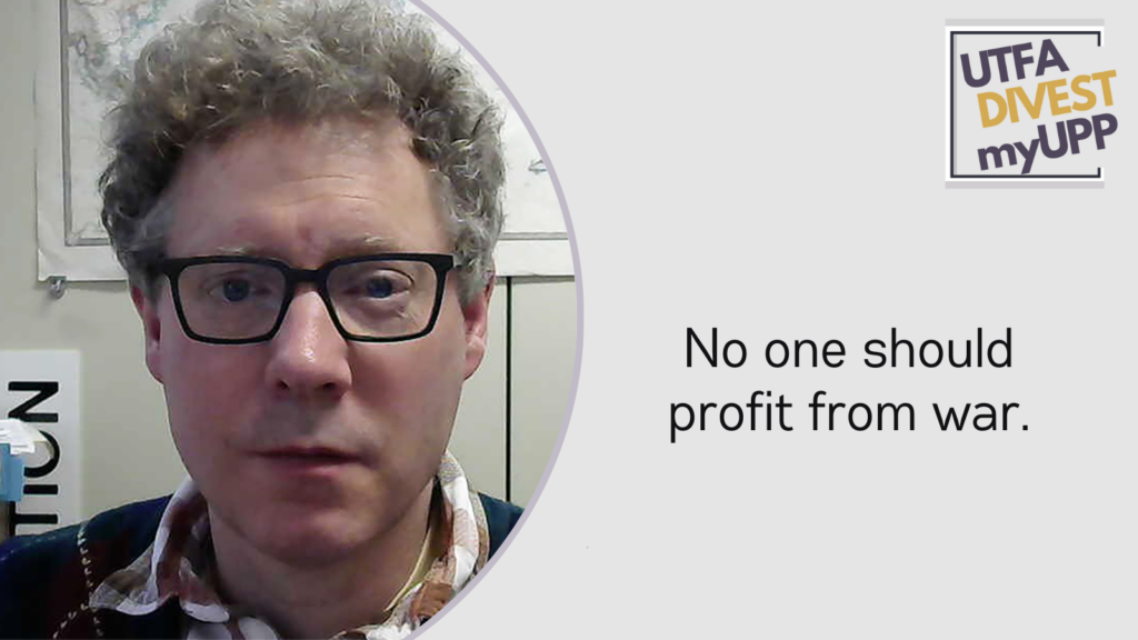 Picture of a white 55-year old man with curly brown-grey hair, dark glasses, and wearing a dark green cardigan. The image has a mostly-white background with a world map on the wall.